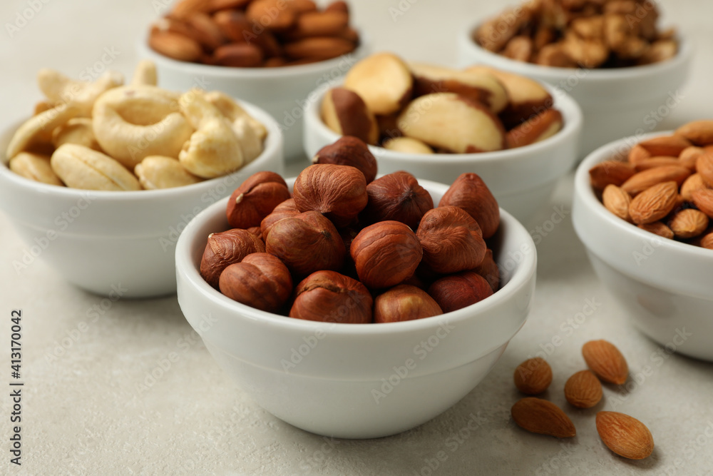 Bowls with different nuts on white textured background, close up Bowls with different nuts on white textured background, close up