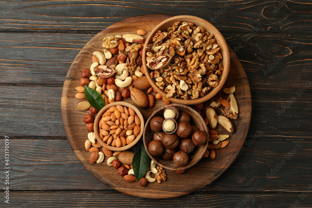Tray with bowls with different nuts on wooden background Tray with bowls with different nuts on wooden background