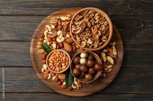 Tray with bowls with different nuts on wooden background