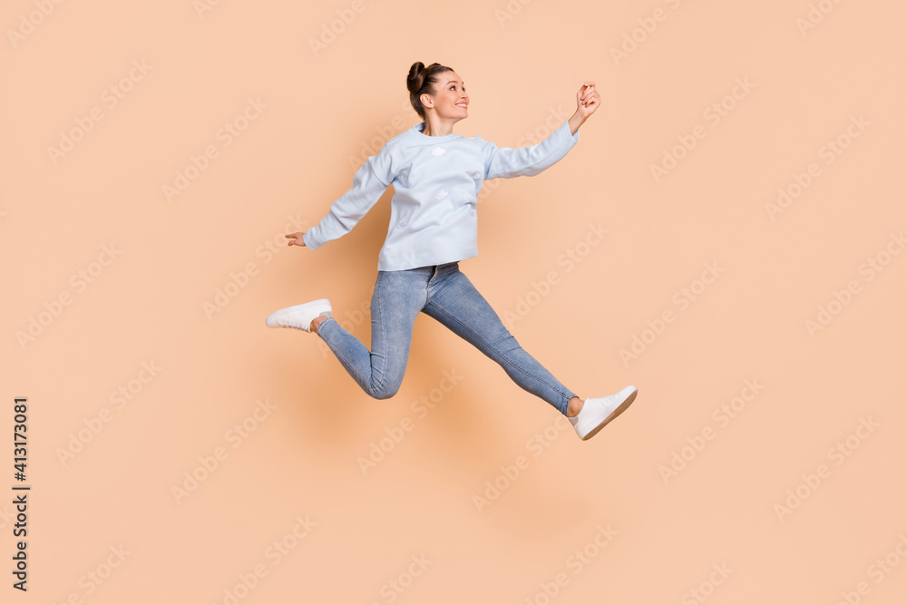 Full size profile photo of optimistic nice brunette lady jump catch wear blue sweater jeans sneakers isolated on beige background