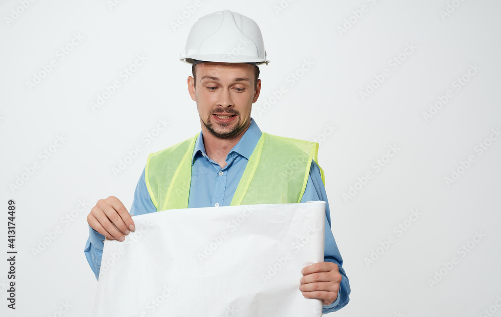 A male civil engineer with a roll of paper in his hands and a white hard hat on his head A male civil engineer with a roll of paper in his hands and a white hard hat on his head