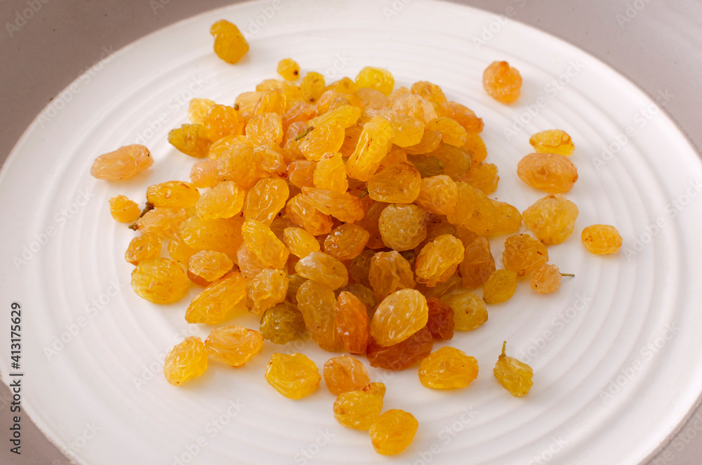 Heap of sweet dried sultana grape on the white plate Heap of sweet dried sultana grape on the white plate