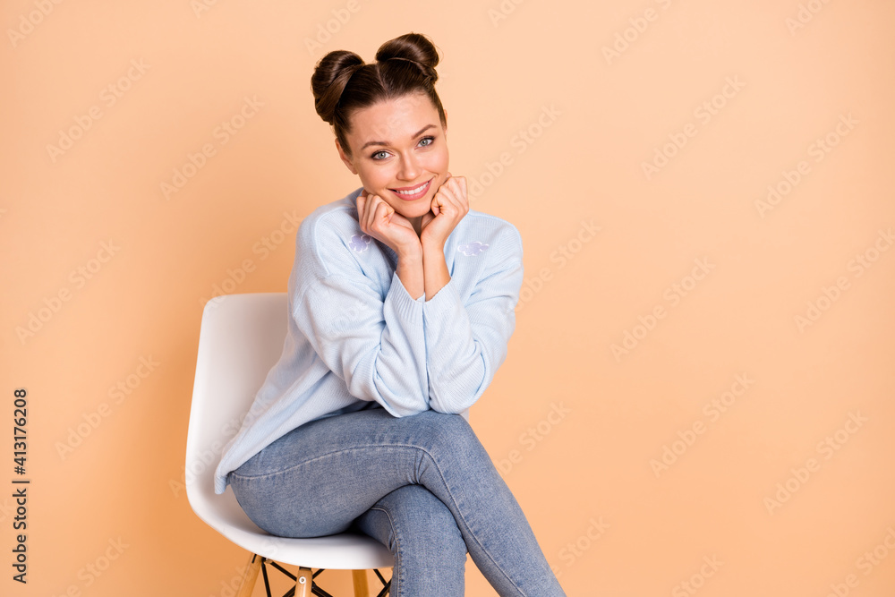 Photo of optimistic cool brunette lady sit hands fists wear sweater jeans isolated on pastel beige color background Photo of optimistic cool brunette lady sit hands fists wear sweater jeans isolated on pastel beige color background