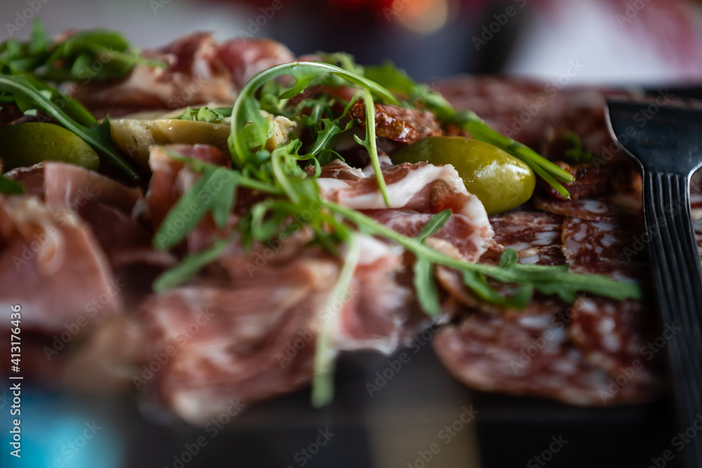 Close-up of basturma sliced into pieces. Dried meat with spices cut into slices. Dried horse meat on a wooden board with rosemary and caraway herbs. Close-up of basturma sliced into pieces. Dried meat with spices cut into slices. Dried horse meat on a wooden board with rosemary and caraway herbs.
