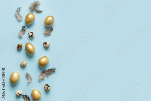 Easter greeting card with golden eggs on blue background with copy space. View from above. Flat lay.