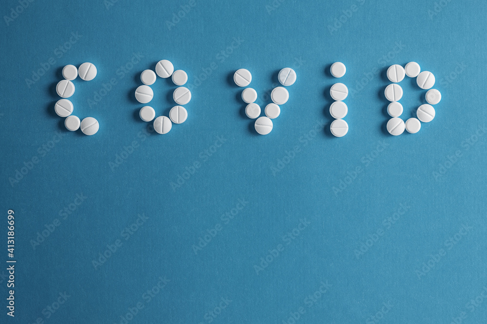 Small pills of different colour and shape arranged in word (covid - 19) on blue background. Small pills of different colour and shape arranged in word (covid - 19) on blue background.