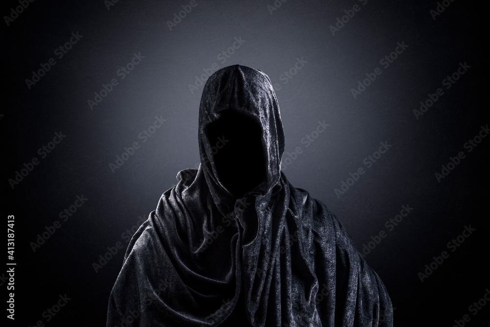 Scary figure with hooded cape in the dark Scary figure with hooded cape in the dark