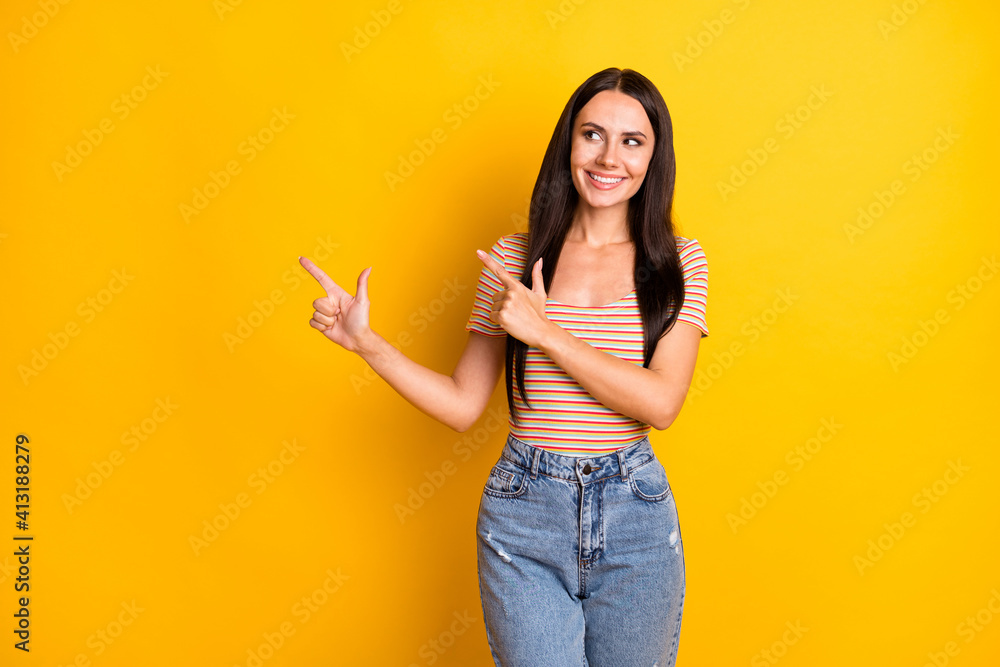 Photo portrait of curious woman smiling showing empty space advising isolated on bright yellow color background Photo portrait of curious woman smiling showing empty space advising isolated on bright yellow color background