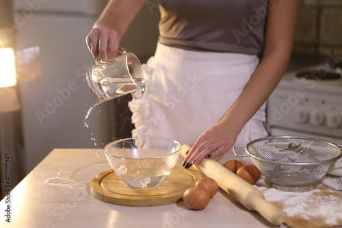 Girl makes dough for dumplings in the kitchen