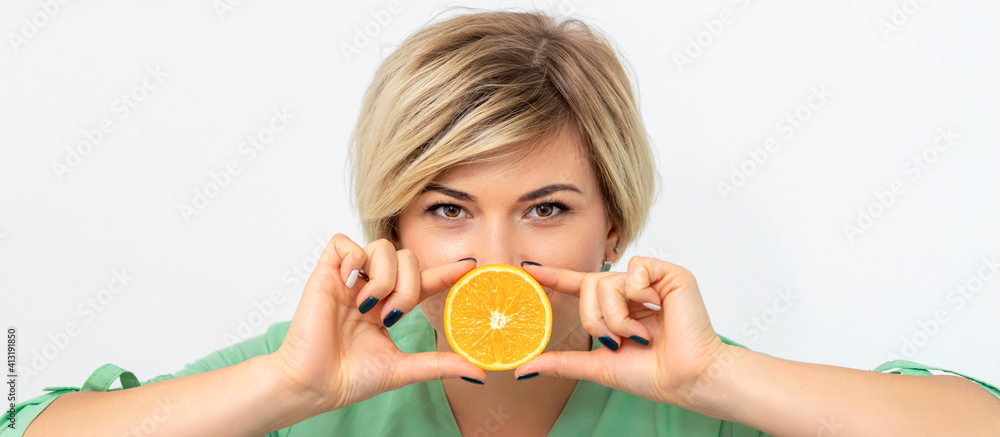 Portrait of female dietitian holding and showing a slice of orange against her lips on a white background Portrait of female dietitian holding and showing a slice of orange against her lips on a white background