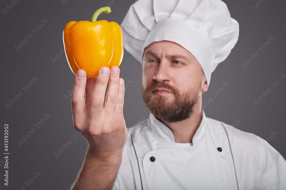 Serious chef examining fresh pepper Serious chef examining fresh pepper
