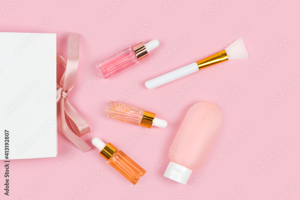 Skin care essence glass bottles and body lotion in plastic container with paper gift shopping bag on pink background. Hydrating anti aging serum, collagen and peptides, bottle with dropper. Cosmetics Skin care essence glass bottles and body lotion in plastic container with paper gift shopping bag on pink background. Hydrating anti aging serum, collagen and peptides, bottle with dropper. Cosmetics