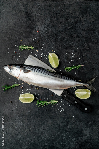 Fresh raw fish mackerel on a knife with spices on a stone background