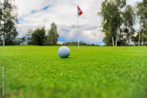 Golf ball on a green golf course with a flag and a hole in the background photo