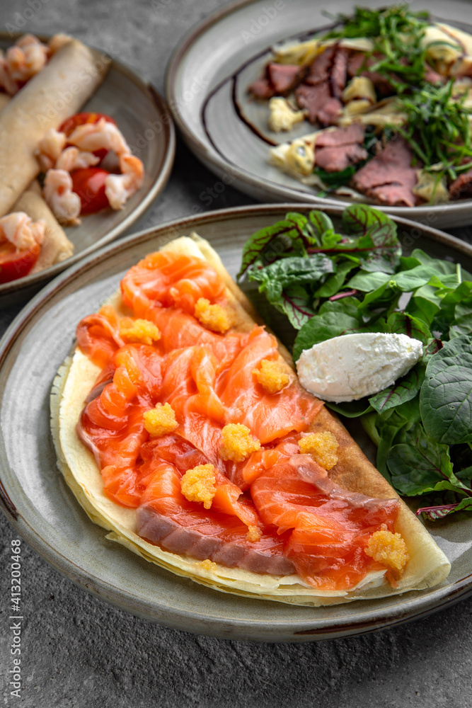 Pancakes with tender fillet of salted salmon with caviar, cheese and herbs. Delicious, hearty, nutritious breakfast. Balanced nutrition for beauty and health. Pancakes with tender fillet of salted salmon with caviar, cheese and herbs. Delicious, hearty, nutritious breakfast. Balanced nutrition for beauty and health.