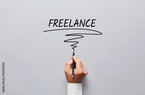 Businessman hand writing freelance on gray background. Freelance job or working as a freelancer photo