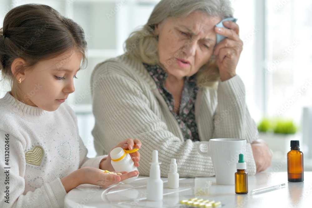 Cute girl giving medicine to sick senior woman Cute girl giving medicine to sick senior woman