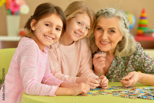 Grandmother with little granddaughters collecting  puzzle