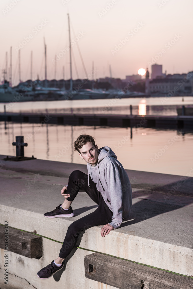 Young redhead man posing at sunset next to a pier dressed casual wearing gray sweatshirt. Young redhead man posing at sunset next to a pier dressed casual wearing gray sweatshirt.
