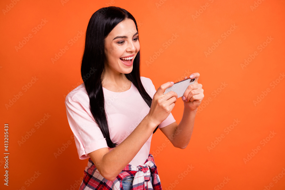 Profile photo of crazy cheerful girl playing games open mouth smile enjoy isolated on orange color background Profile photo of crazy cheerful girl playing games open mouth smile enjoy isolated on orange color background