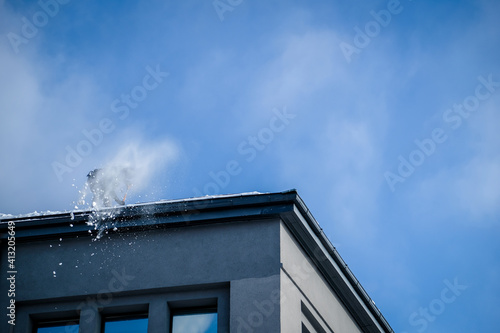 Team of male workers clean roof of building from snow with shovels in securing belts. Selective focus © Viesturs
