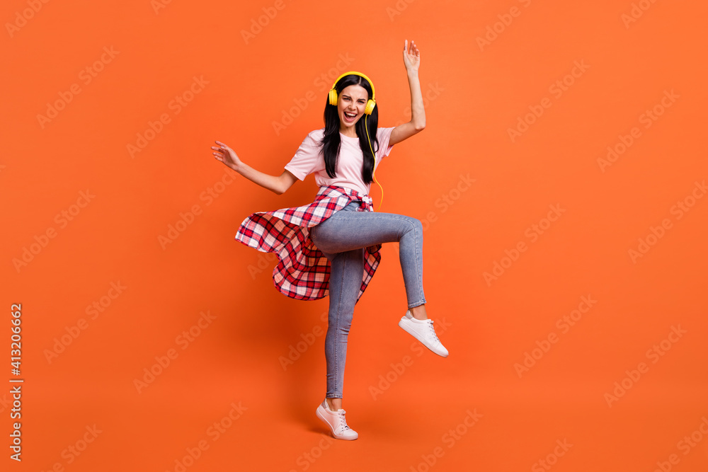 Full body profile portrait of excited pretty girl raise hands knee open mouth smile isolated on orange color background