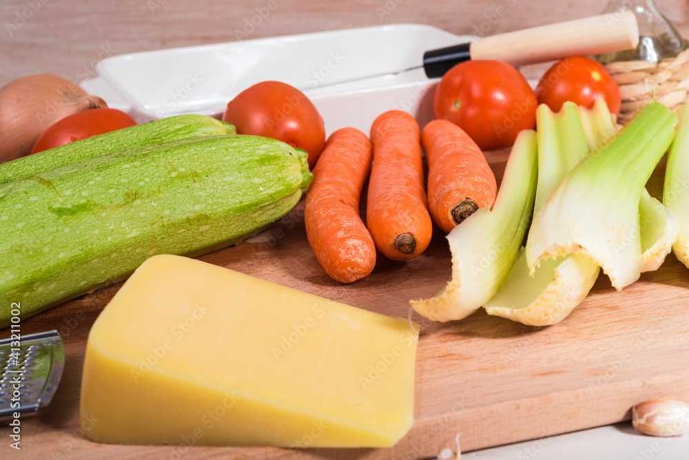 Ingredients for making baked zucchini rolls with vegetables and cheese on a wooden kitchen board Ingredients for making baked zucchini rolls with vegetables and cheese on a wooden kitchen board