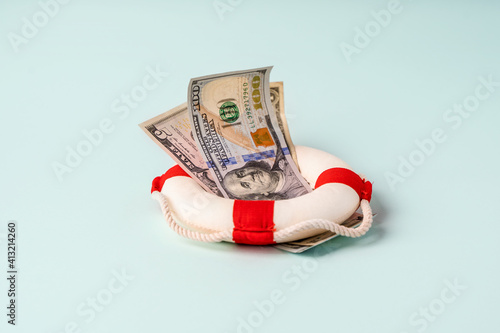 A lifebuoy with banknotes lie on a blue background, the concept of assistance and security in finance