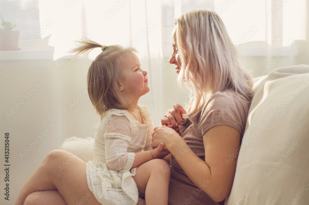 Mother and daughter toddler playing, kissing, hugging and smiling, enjoy at the sofa, spending time at home. Moments of tenderness . Happy loving family. Good time at home. Family single mother Mother and daughter toddler playing, kissing, hugging and smiling, enjoy at the sofa, spending time at home. Moments of tenderness . Happy loving family. Good time at home. Family single mother