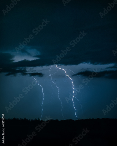 Photo of the lightning in the night sky. Powerful energy, natural electricity. Thunder in the dark, bad rainy weather. Dramatic view on the sky.
