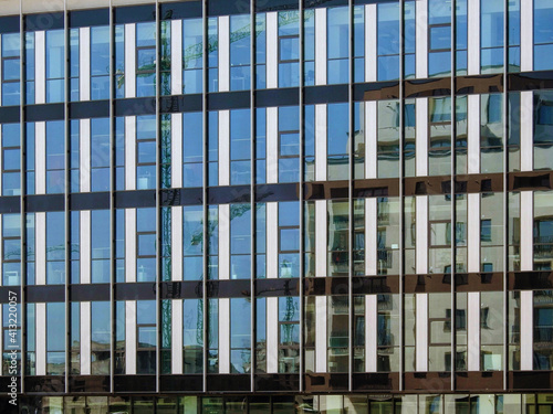 Reflection of a residential buildings in the large glass wall of a modern office structure