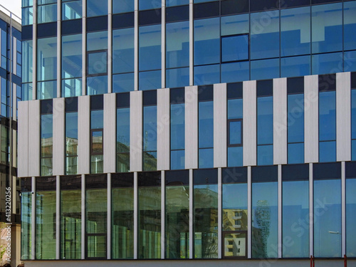 Reflection of residential buildings in the large glass wall of a modern office  structure