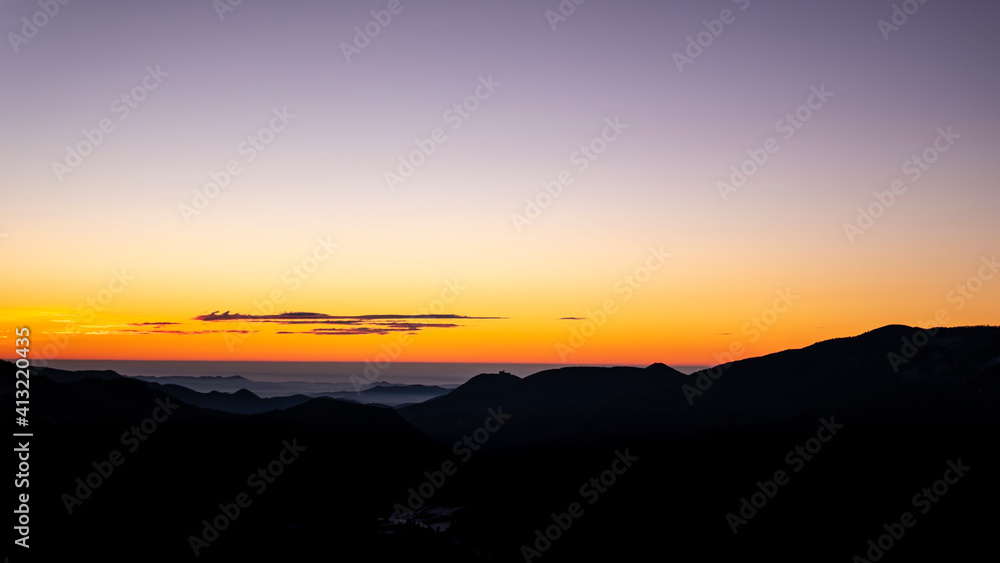 Orange sunrise sky landscape with mountain silhouettes