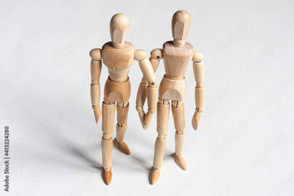 two wooden mannequins holding hands and stepping forward two wooden mannequins holding hands and stepping forward