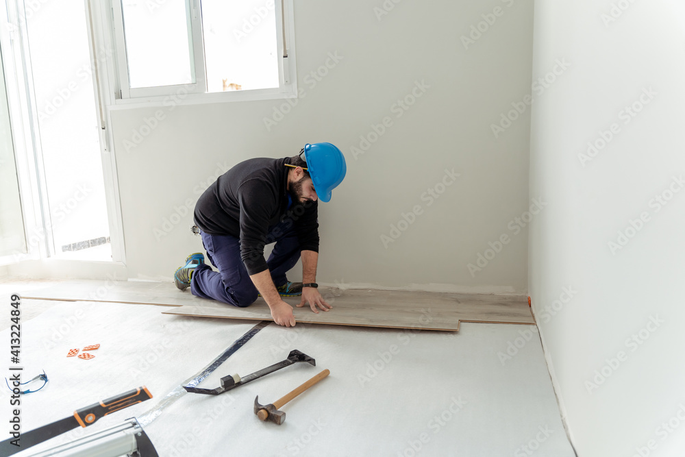 Man worker assembling laminate flooring. Man worker assembling laminate flooring.