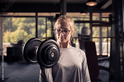 famle athlete is doing a workout with a heavy dumbbell in a gym © Joachim