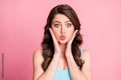 Close up portrait of charming young lady hands palm on cheek kiss blue tank-top isolated on pink color background