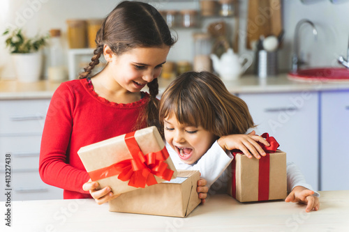 The children received gifts for the holiday. Happy kids open gift boxes for Valentine's Day. Brother and sister have fun and rejoice in surprise © Alex Desanshe