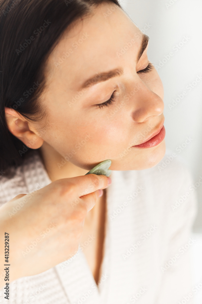 Young woman doing face Gua sha - chinese traditional massage Young woman doing face Gua sha - chinese traditional massage