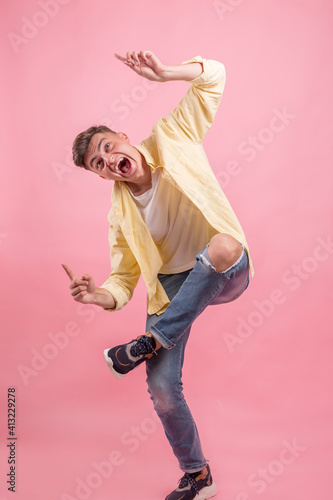 Portrait of a satisfied young man celebrating success isolated over pink background