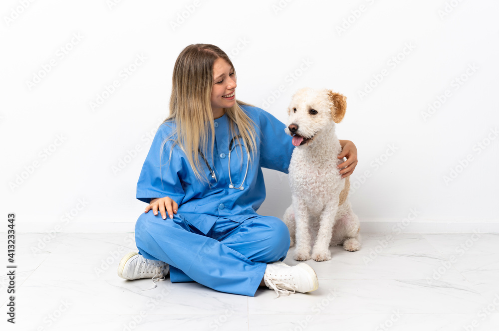 Young veterinarian woman with dog sitting on the floor looking to the side and smiling Young veterinarian woman with dog sitting on the floor looking to the side and smiling