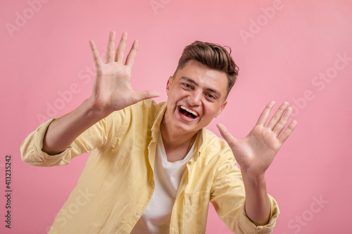 Happy smiling young man presenting and showing your text or product isolated on pink background