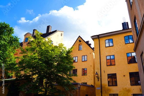 Photography Cozy courtyard with in yellow houses and green trees in the Old Town of Stockholm