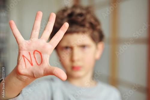A little boy shows a palm with a prohibitory inscription "No"