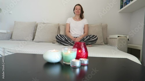 Woman sit on sofa meditation breathing techniques, mindfulness, yoga breathing. Candles lit, living room, self care concept.