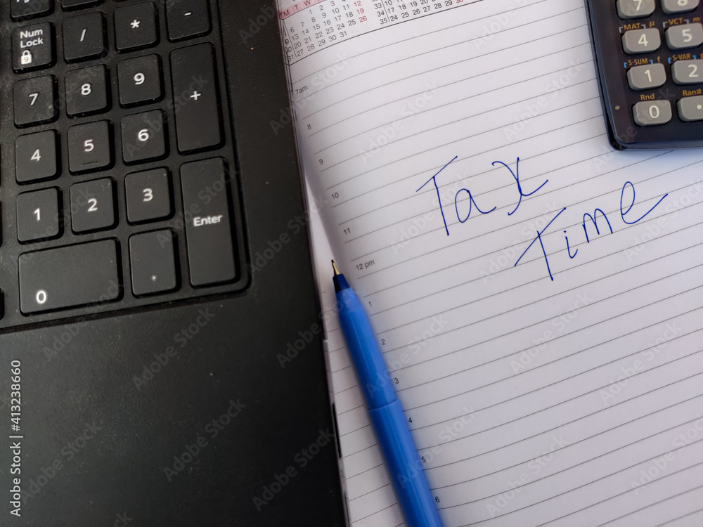 A diary with text TAX TIME and calculator,pen,laptop.