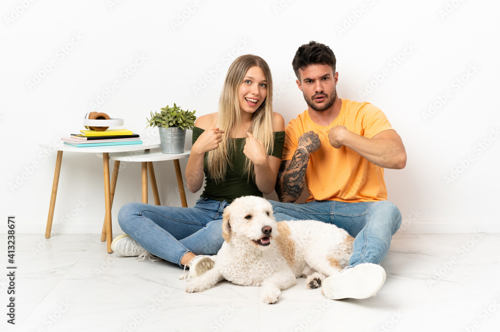 Young caucasian couple with dog staying at home with surprise facial expression Young caucasian couple with dog staying at home with surprise facial expression