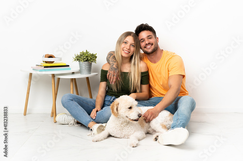 Young caucasian couple with dog staying at home hugging
