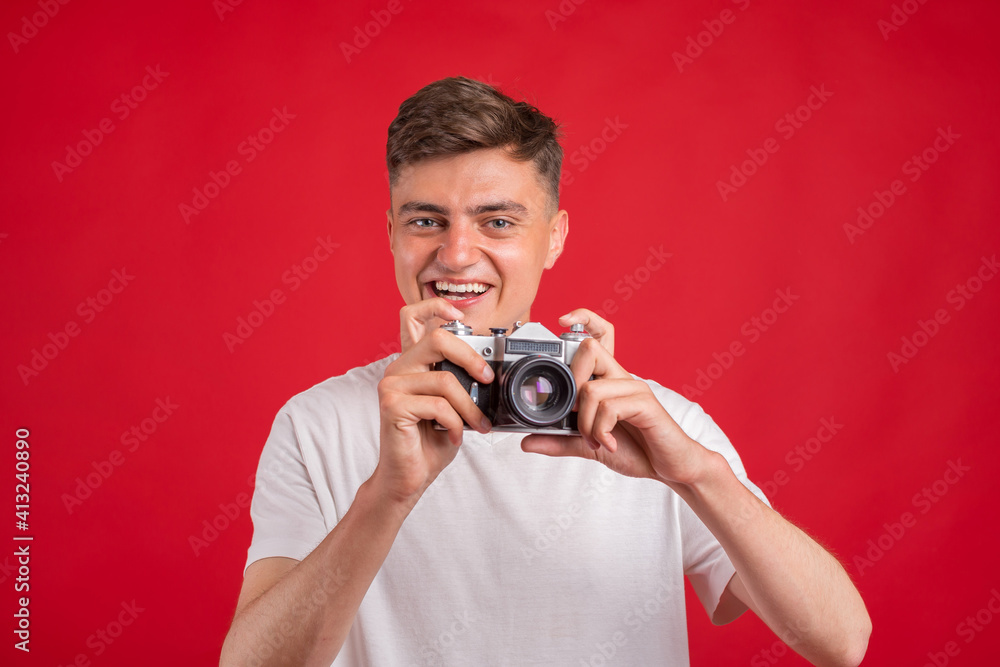 Obraz premium Say cheese! Young man take photo with retro dslr camera looking at camera over gray abackground. Portrait of positive man in hat with retro camera standing isolated