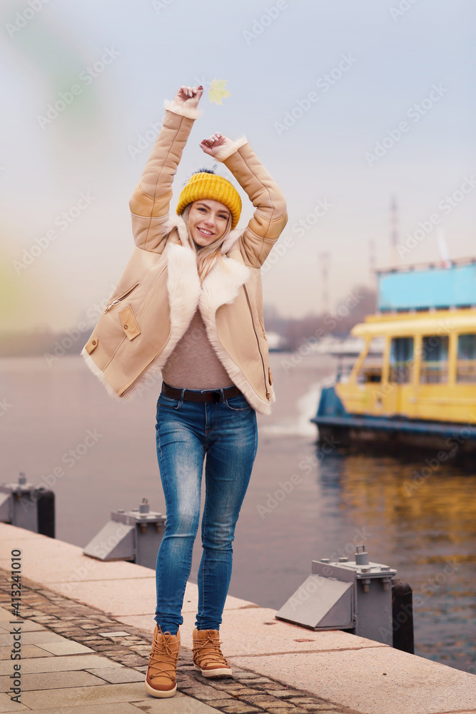  blond model girl in knitted yellow hat and coat with coffee paper glass close up portrait on steamer background
